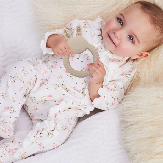 anneau de dentition bebe creme tenu par bebe allonge