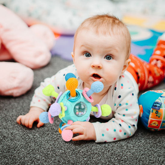 bebe allonge ventre avec hochet bebe pres visage