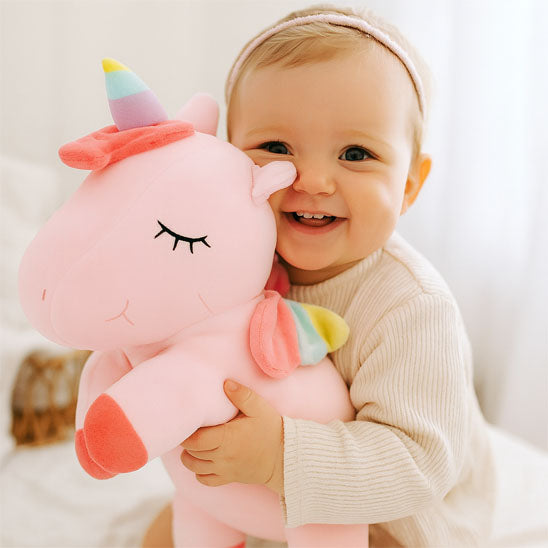 bebe fille tient peluche licorne dans bras