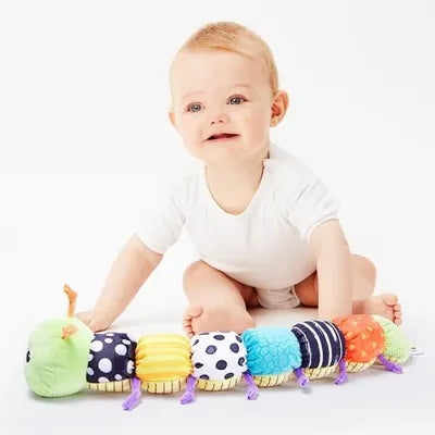 bebe accroupi joue avec hochet chenille au sol