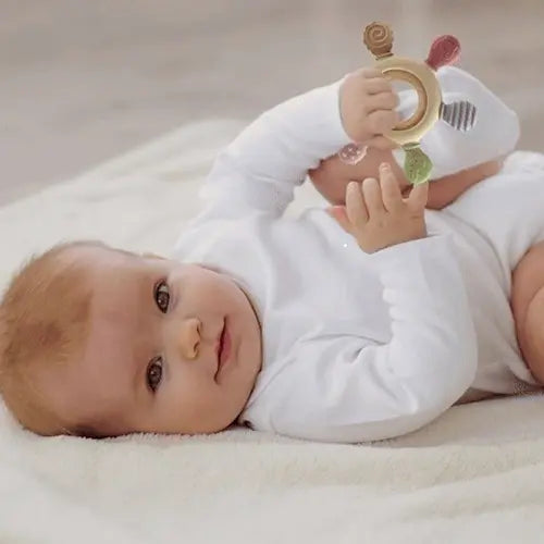 bébé allonge dos lit tient anneau de dentition