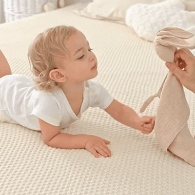 bebe allonge lit regarde doudou bebe lapin main maman