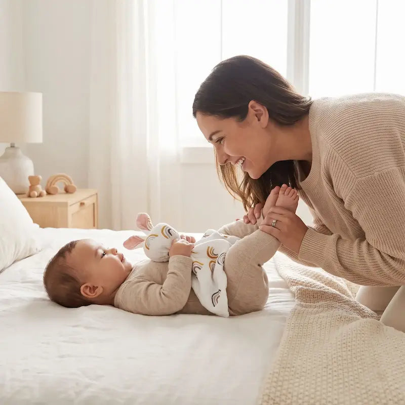 bébé allongé lit tient doudou bebe maman joue pieds bébé