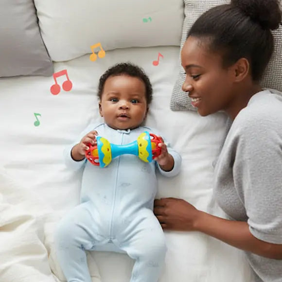 bébé allongé lit tient hochet bebe maman allongée sourit bébé