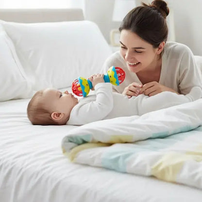 bébé allongé lit tient hochet bebe près bouche maman surveille