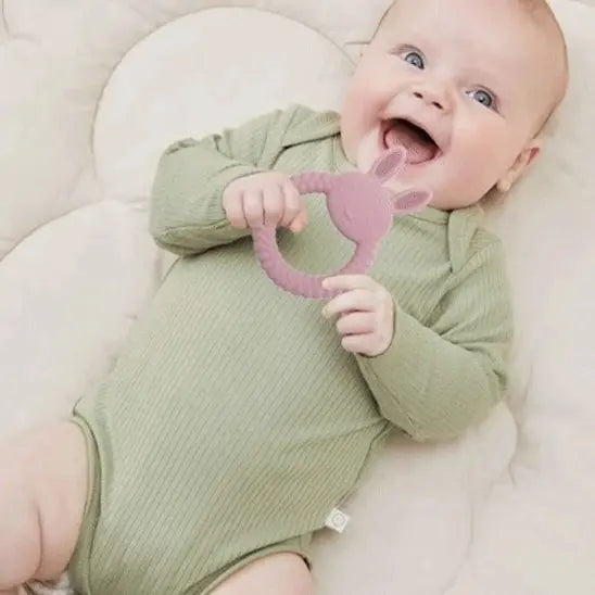 bébé allongé tient anneau de dentition bébé lapin rose