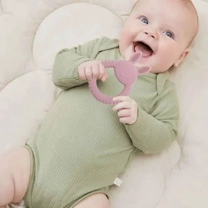 bébé allongé tient anneau de dentition bébé lapin rose