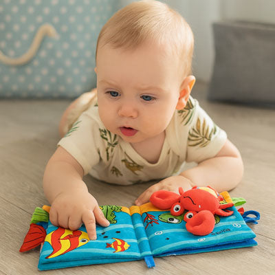 bebe allonge ventre regarde livre bebe en tissus