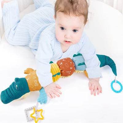 bebe allonge ventre sur hochet crocodile dans berceau