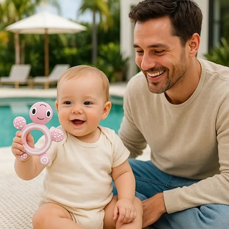 bébé assis bord piscine tient anneau dentition bebe papa sourit