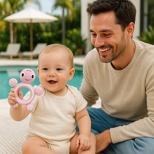 bébé assis bord piscine tient anneau dentition bebe papa sourit