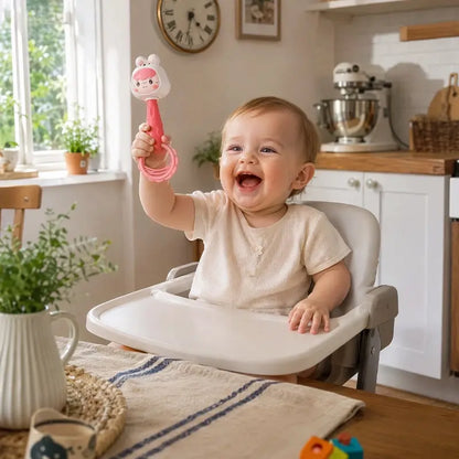 bébé assis chaise haute tient main hochet bébé lapin rose