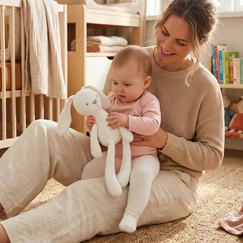 bébé assis maman tapis tient doudou lapin blanc