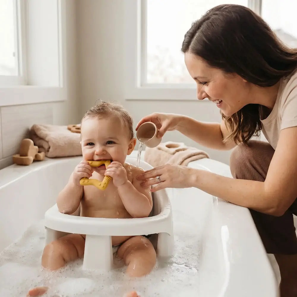 bébé assis siège baignoire mord anneau dentition bébé maman surveille