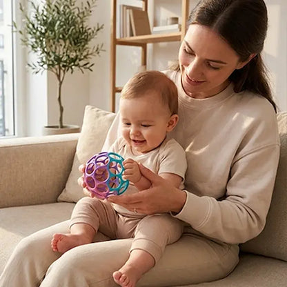 bébé assis sur maman canapé tient balle sensorielle bebe