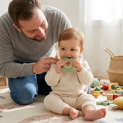 bebe assis tapis mordille anneau de dentition papa surveille bebe