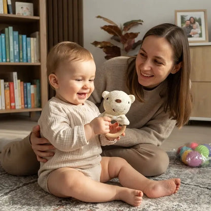 bébé assis tapis regarde hochet bébé maman tient bébé
