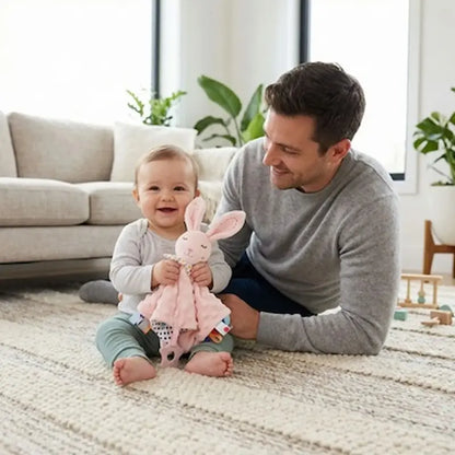 bébé assis tapis salon tient doudou lapin papa sourit
