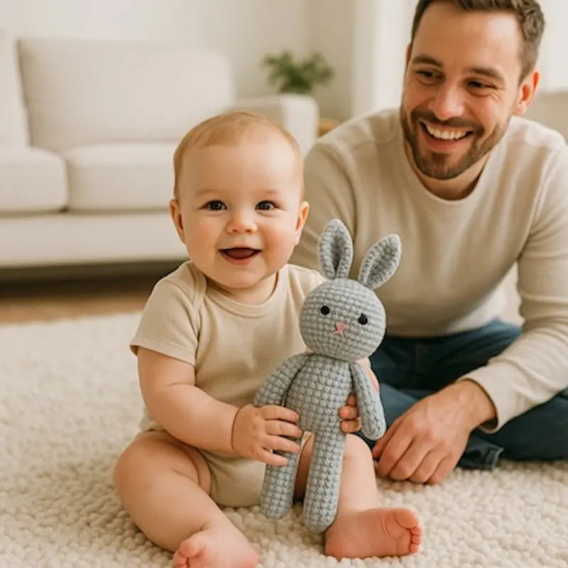 bébé assis tapis sol tient doudou lapin papa sourit