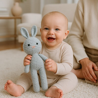 bebe assis tapis tient lapin doudou bleu