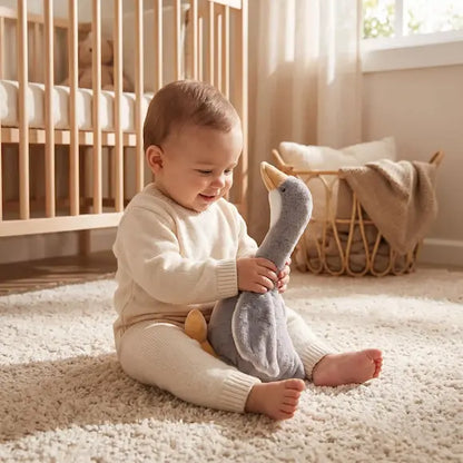 bébé assis tapis tient mains peluche bebe oie grise
