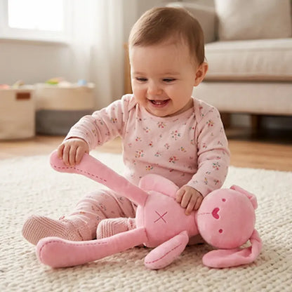 bébé assis tapis tient patte doudou lapin rose