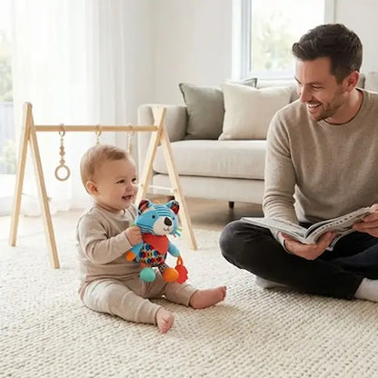 bébé assis tapis tient peluche bebe raton laveur papa sourit