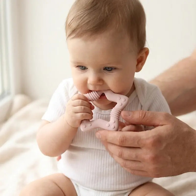 bébé assis tenu par parent mord anneau dentition bébé rose