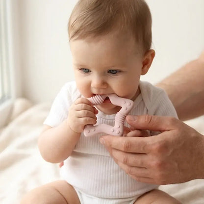 bébé assis tenu par parent mord anneau dentition bébé rose