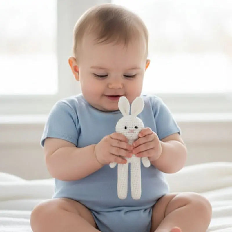 bébé assis tient doudou lapin blanc