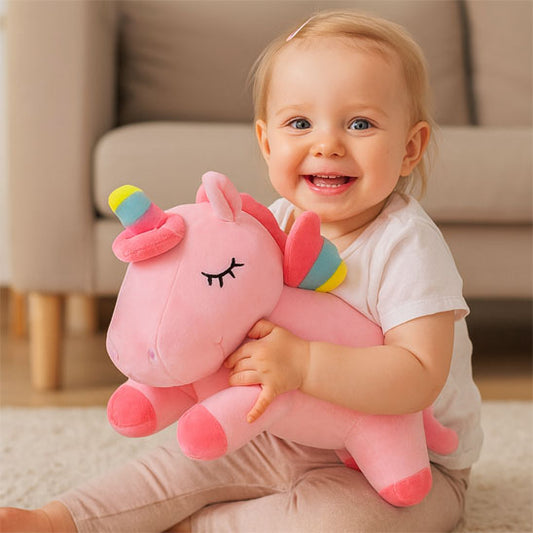 bebe assise tapis salon tient peluche licorne
