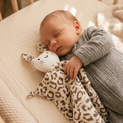 bebe dort sur cote main posee sur doudou bebe leopard