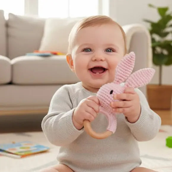 bébé heureux tient hochet bebe lapin rose