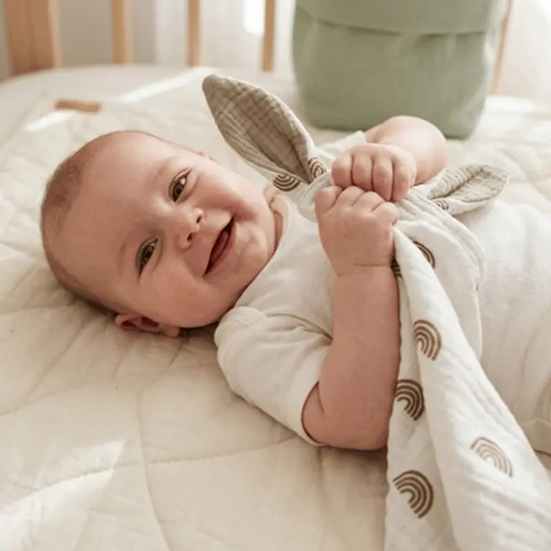 bébé joyeux allongé berceau tient doudou bebe oreilles kaki