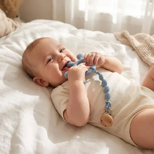 bébé souriant allongé dos berceau tient anneau dentition bébé