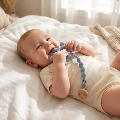 bébé souriant allongé dos berceau tient anneau dentition bébé