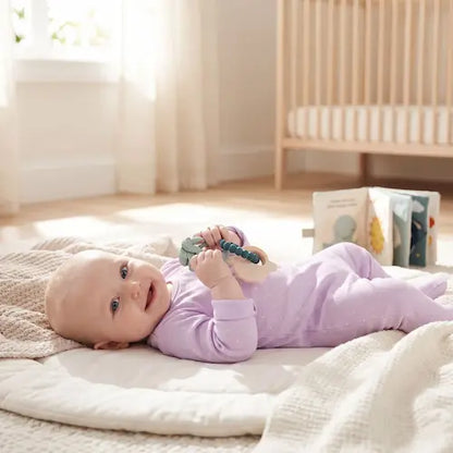 bébé souriant allongé dos tapis tient anneau dentition bébé