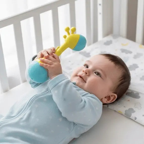 bébé sourit allongé berceau tient hochet bébé