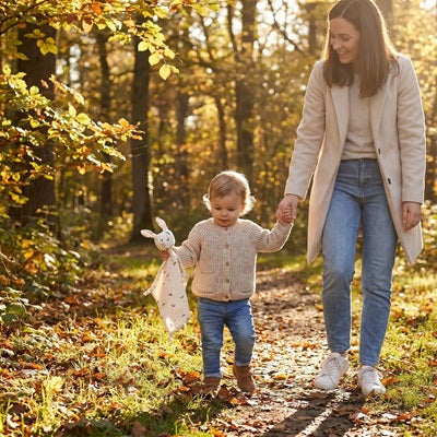 bebe tient doudou lapin maman tient main bebe promenade foret