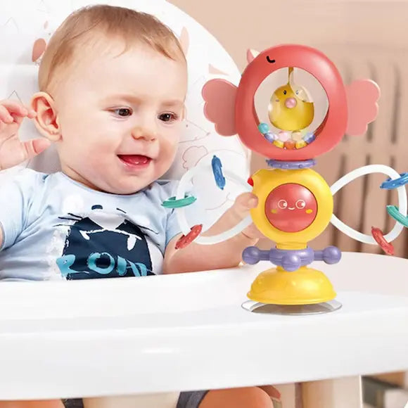 bébé tient hochet fixe sur chaise haute