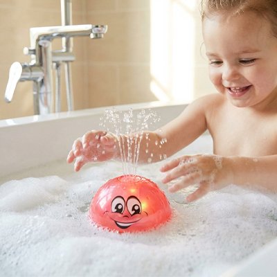enfant joyeux regarde jouet de bain bebe rouge flotte lumineusement