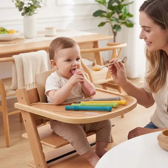 maman donne repas bébé chaise haute mord anneau dentition bébé