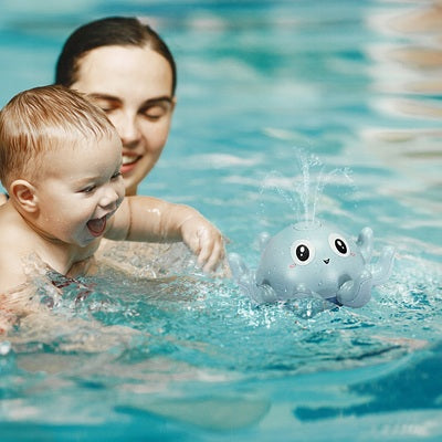 maman tient bebe dans piscine regarde jouet baignoire bebe flotte