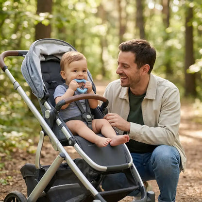 papa accroupi regarde bébé assis poussette mord anneau dentition bébé