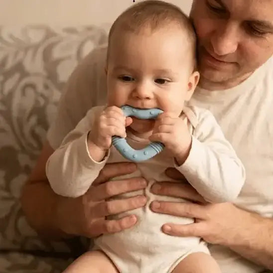 papa tient bébé mordille anneau dentition bébé coeur bleu
