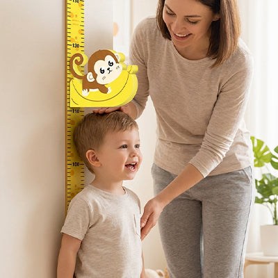 petit garcon debout contre toise enfant signe maman mesure