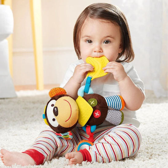 petite fille assise mordille peluche hochet singe