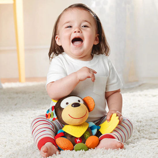 petite fille joyeuse assise joue avec peluche hochet