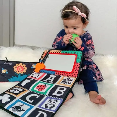 petite fille mord hochet dentition avec livre tissu bebe